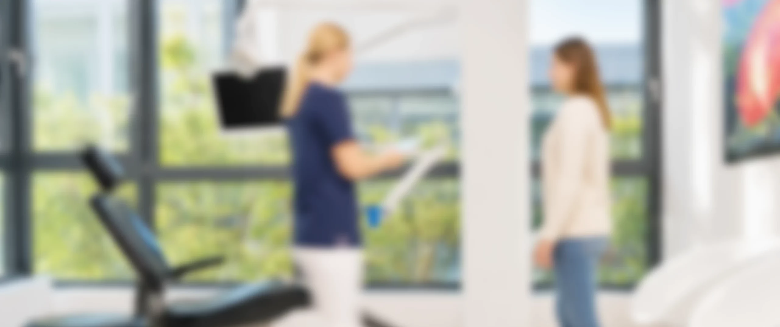 Praxismitarbeiterin und Patientin sprechen im Behandlungszimmer von DEIN DENTAL Karlsruhe